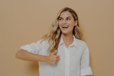 Portrait of smiling young woman against wall