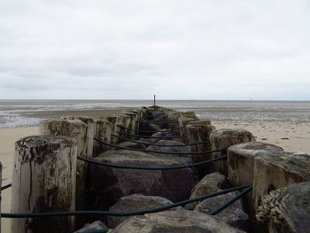 Wooden posts on beach against sky