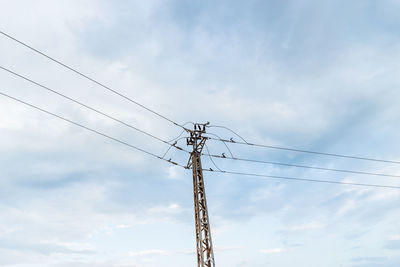 Low angle view of power lines against cloudy sky