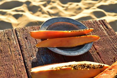 Fresh papaya slices on pewter plate on rustic wood table on sand beach  sea of cortez baja, mexico