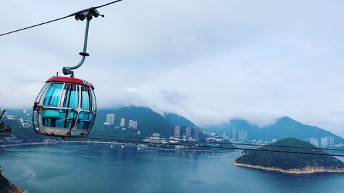 Overhead cable car over lake against sky in town