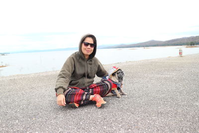 Woman sitting with pug at beach