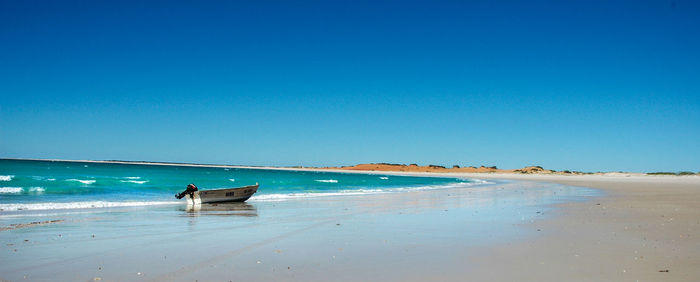 Scenic view of beach against clear blue sky