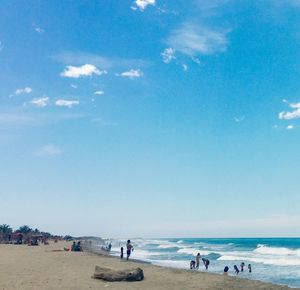 People on beach against blue sky