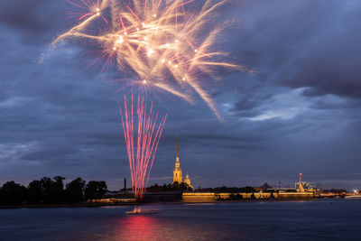 Firework display over river against sky at night