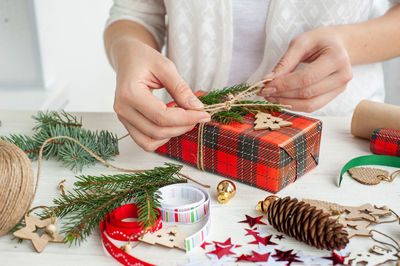 Decorating christmas presents. a woman decorates a box with a christmas gift spruce branch.