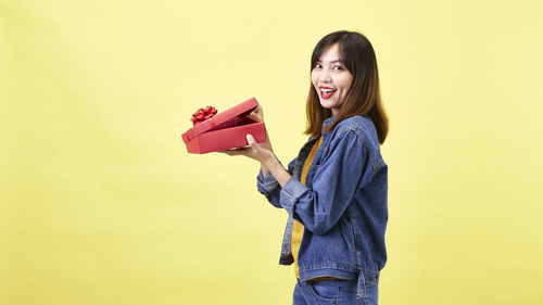 Portrait of smiling young woman against gray background