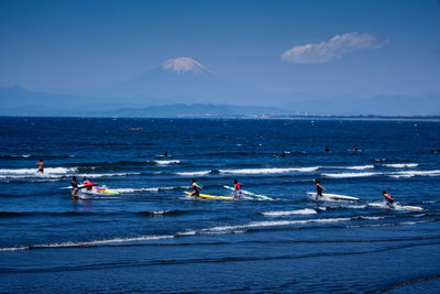 People surfing in sea against sky