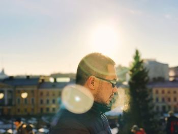 Close-up of man wearing sunglasses in city against sky