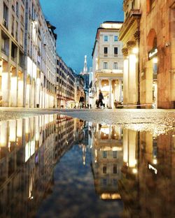 Reflection of buildings in puddle at night