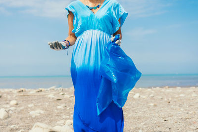 Selective focus on a young activist on the beach wears gloves and a garbage bag, 
earth day concept.