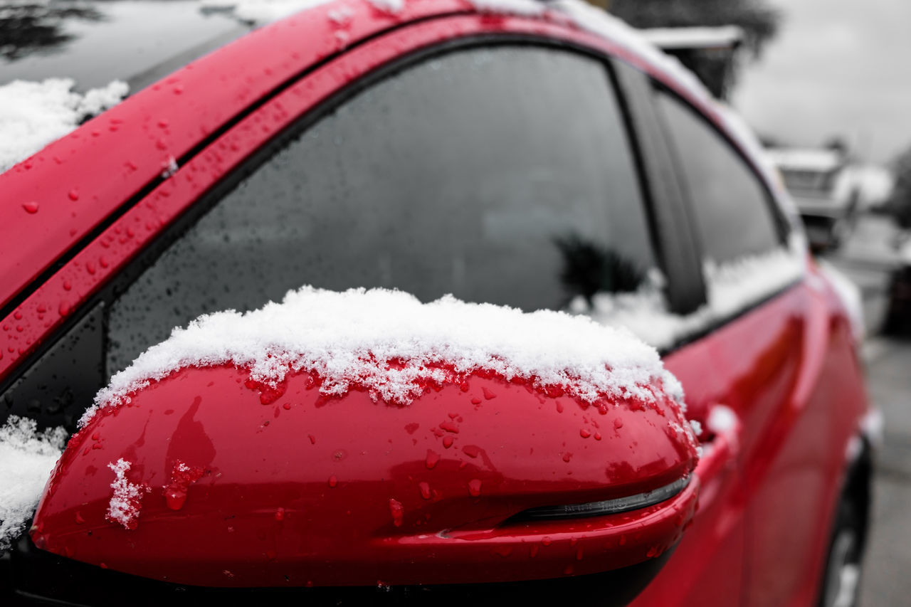 CLOSE-UP OF SNOW ON RED CAR IN CITY