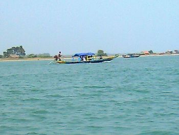 Boats in calm sea against clear sky