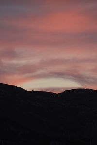 Scenic view of silhouette mountains against orange sky