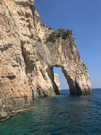 Rock formation in sea against clear blue sky