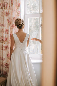 Rear view of woman standing against window