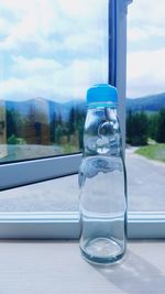 Close-up of water bottle on window sill