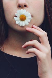 Midsection of woman carrying white flower in mouth