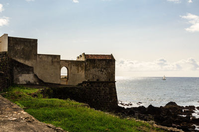 Old building by sea against sky