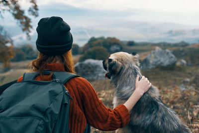 Rear view of woman with dog looking at winter