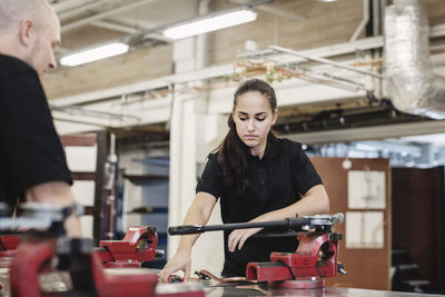 Auto mechanic teacher assisting female student in workshop