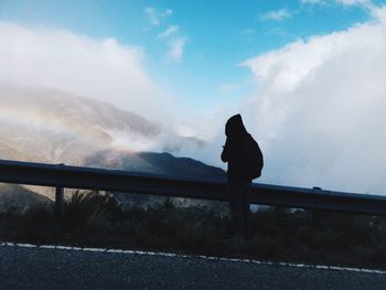 People standing on mountain against cloudy sky