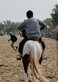 Rear view of man riding horse