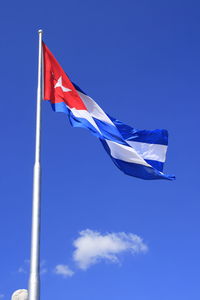 Low angle view of cuban flag against blue sky