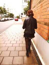 Rear view of woman walking on sidewalk