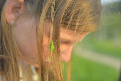 Romantic shot of a blonde girl with a grasshopper in her hair.
