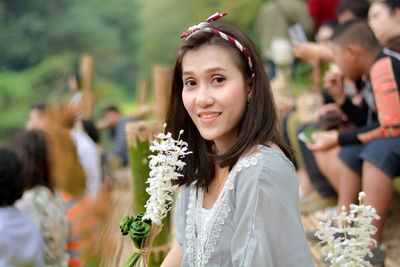 Portrait of smiling woman holding decoration while sitting outdoors