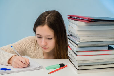 Teenage girl writing on book at home