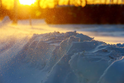 Close-up of snow covered field during sunset