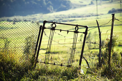 Fence on grassy field during sunny day