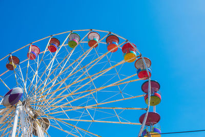 Low angle view of ferris wheel against clear blue sky