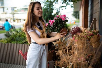 Portrait of young woman standing by plants