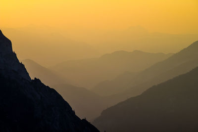 Scenic view of mountain range in foggy weather during sunset