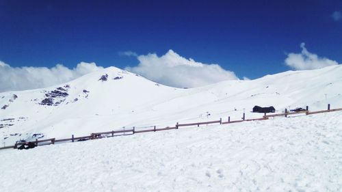 Scenic view of snow covered mountains against blue sky