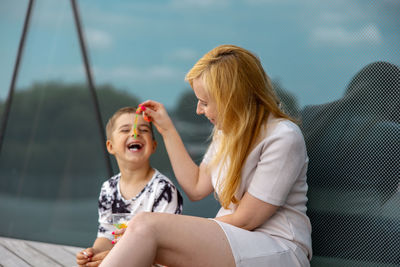 Happy blond woman and little boy sitting on terrace and eating sweets. mother and son