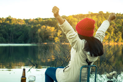 Rear view of woman with arms raised in lake