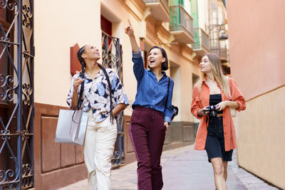 Happy woman gesturing while walking with friends in city