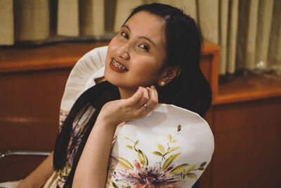 Portrait of smiling young woman sitting at home