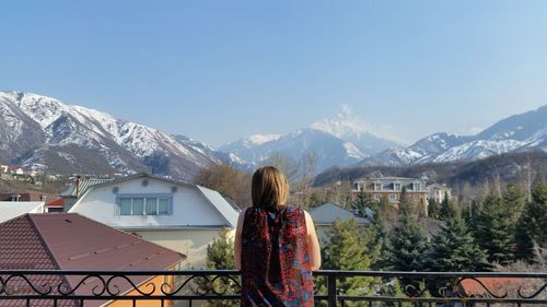 Rear view of woman standing on snowcapped mountain