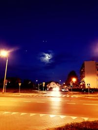 Illuminated street against sky at night