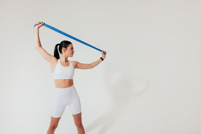 Full length of woman exercising against white background