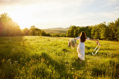 Rear view of woman walking on field against sky