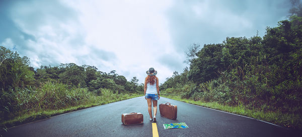 Rear view of woman walking on road against sky