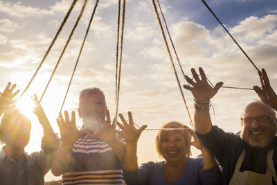 Low angle view of people holding strings against sky during sunset