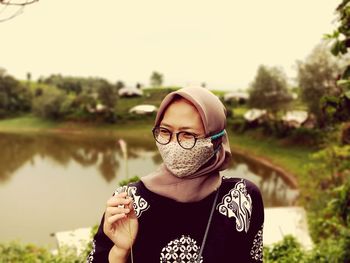 Woman wearing headscarf and mask standing in park