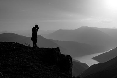 Silhouette man standing on mountain against sky